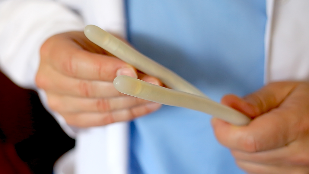 Médico segurando uma prótese peniana maleável, para falar sobre os candidatos ideais