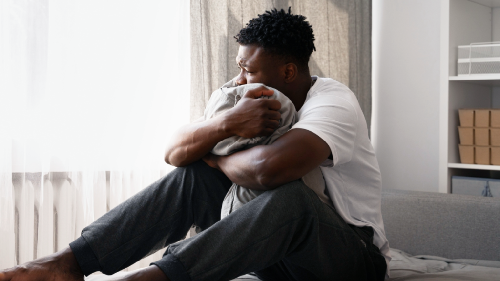 Homem abraçado ao travesseiro, sofrendo com a varicocele