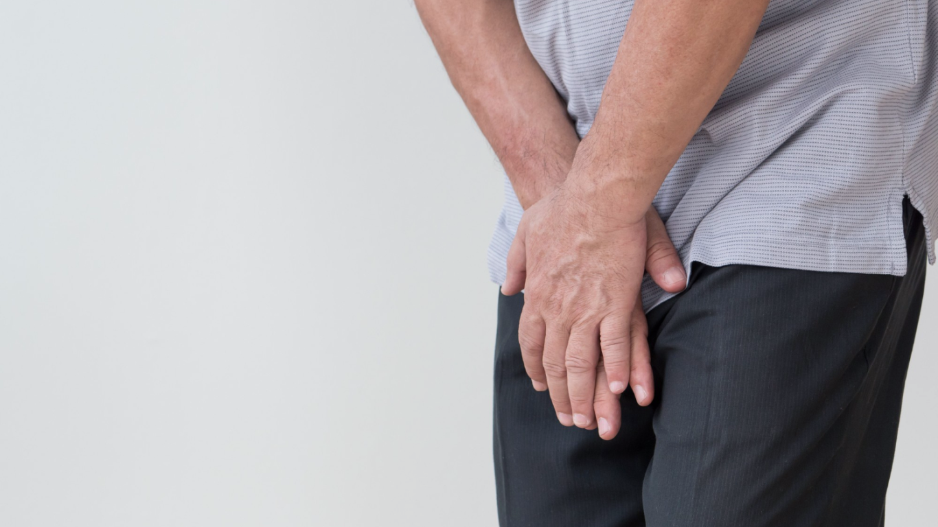 Homem com as mãos sobre os testículos, sentindo dor