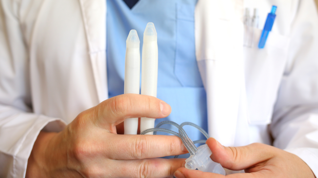 Médico segurando uma prótese peniana, falando sobre suas indicações