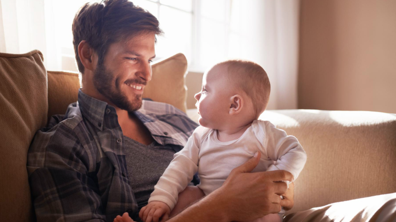 Homem no sofá com criança no colo, feliz por ter filhos de novo
