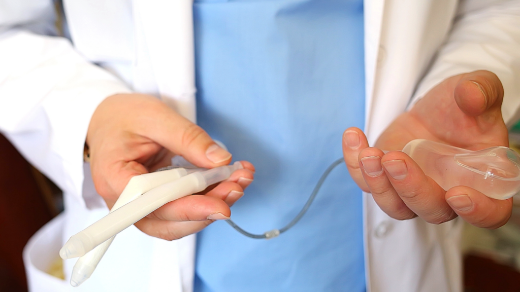 Médico mostrando tipos de próteses penianas disponíveis