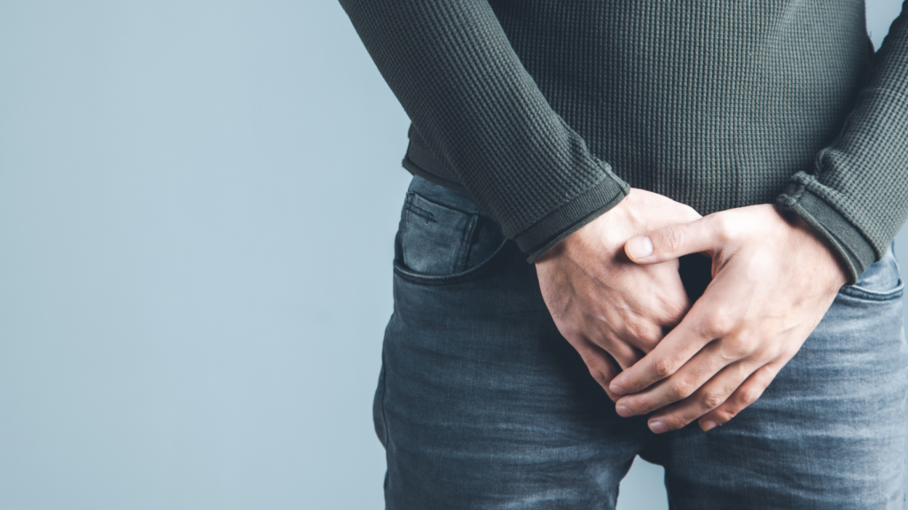 Homem com as mãos na região genital, pensando se é normal o pênis ser torto