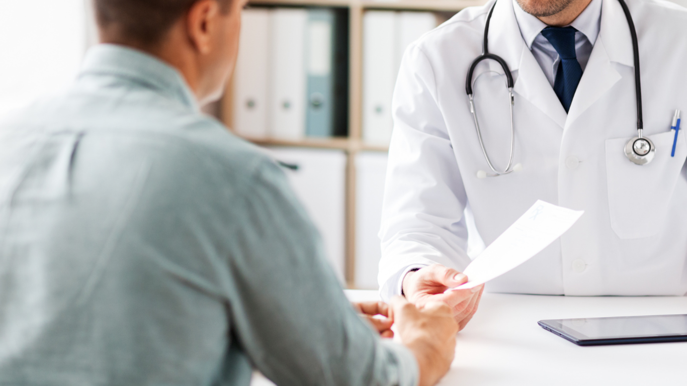 Paciente masculino em consulta com médico urologista, questionando se Peyronie tem cura.